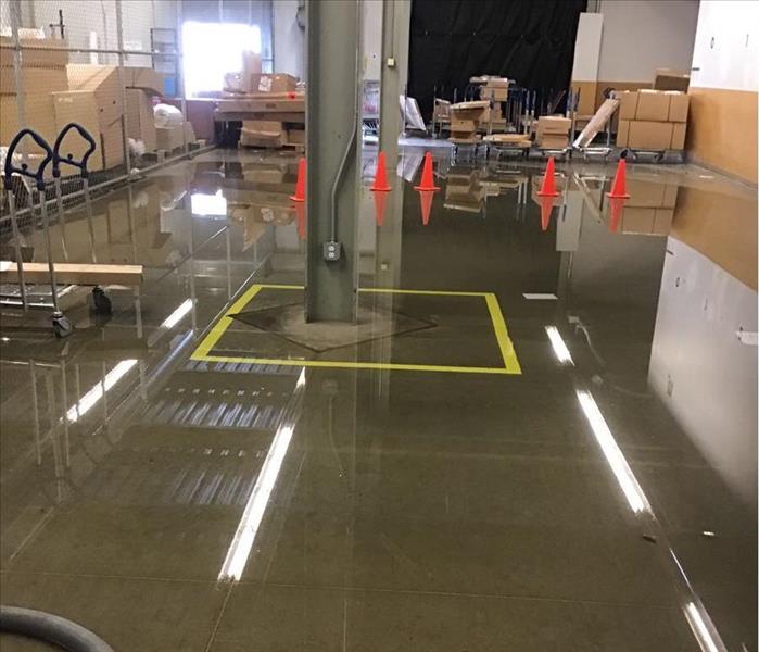 Wet concrete floor with orange cones and brown boxes in the background.
