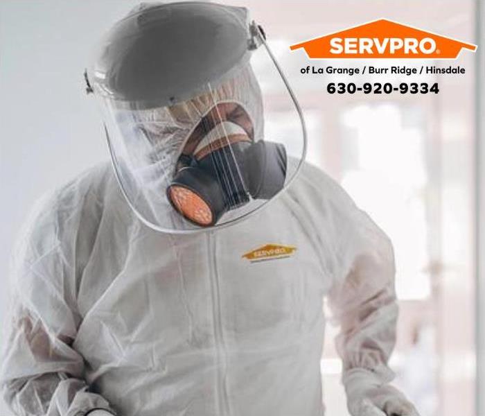 A SERVPRO employee in a white hazmat suit.